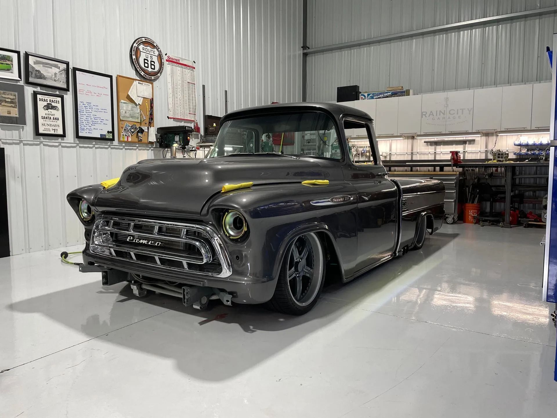 Black vintage custom pickup truck in a workshop garage with white floors and wall-mounted signs