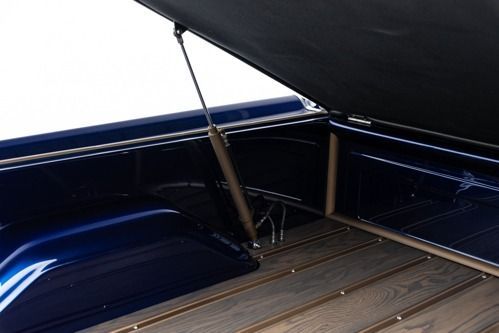 Open truck bed with a raised cover and a fishing rod secured inside