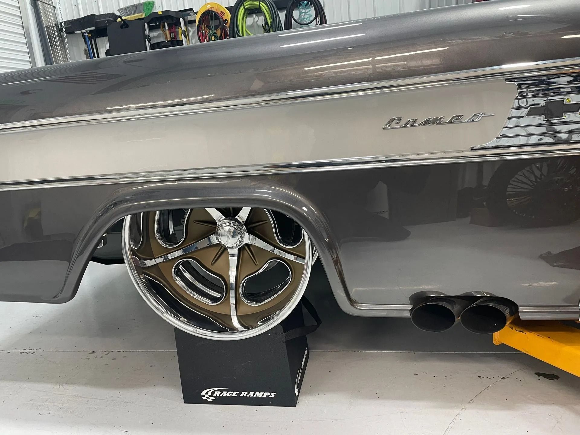 Gray classic car side panel with polished chrome wheel on a display stand