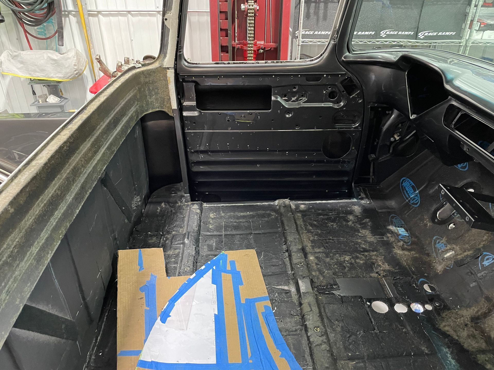Empty black truck bed with a cardboard box covered in blue tape near the front left corner
