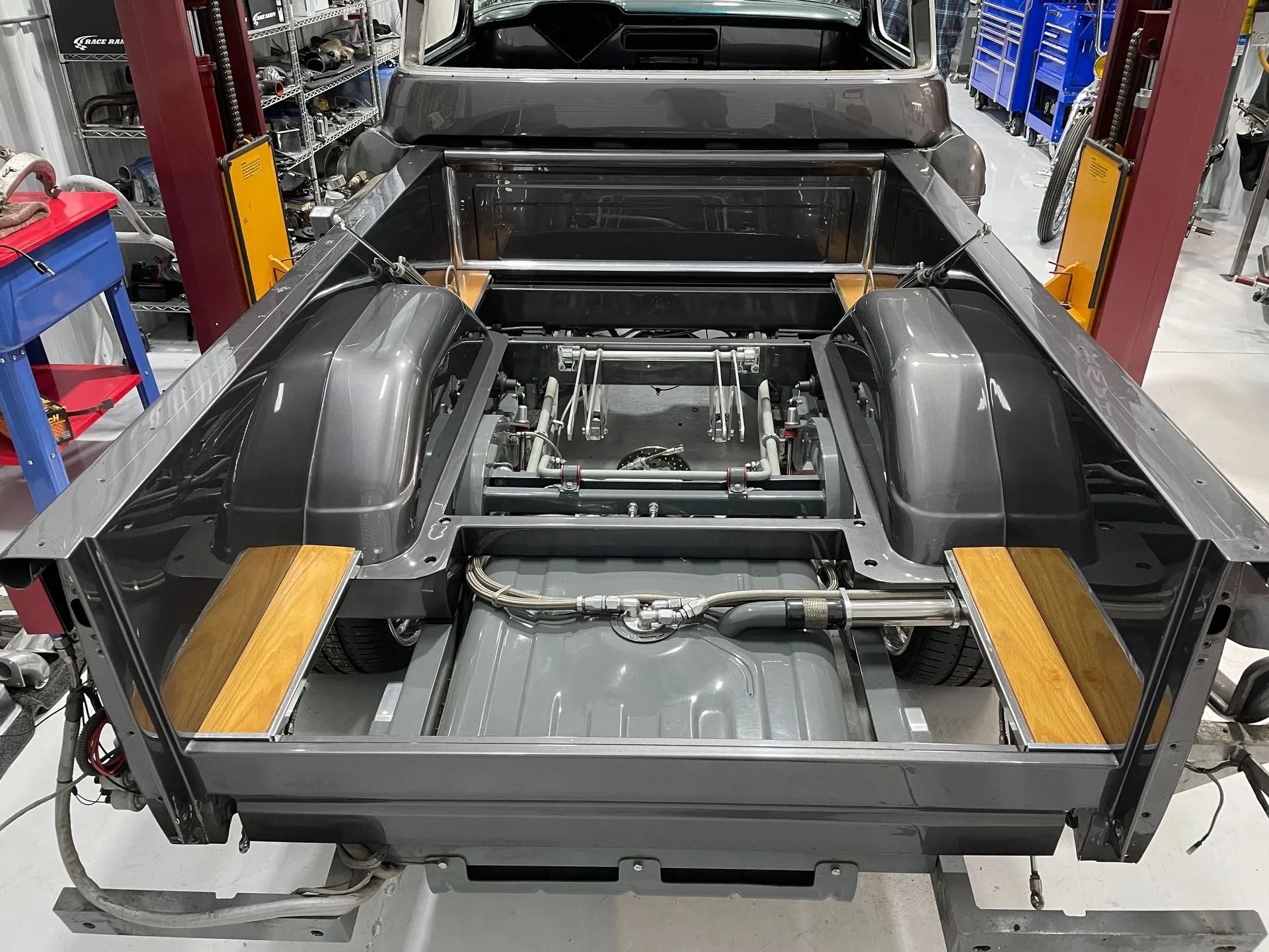 Empty car chassis on an assembly line in a factory, with black frame and exposed components.
