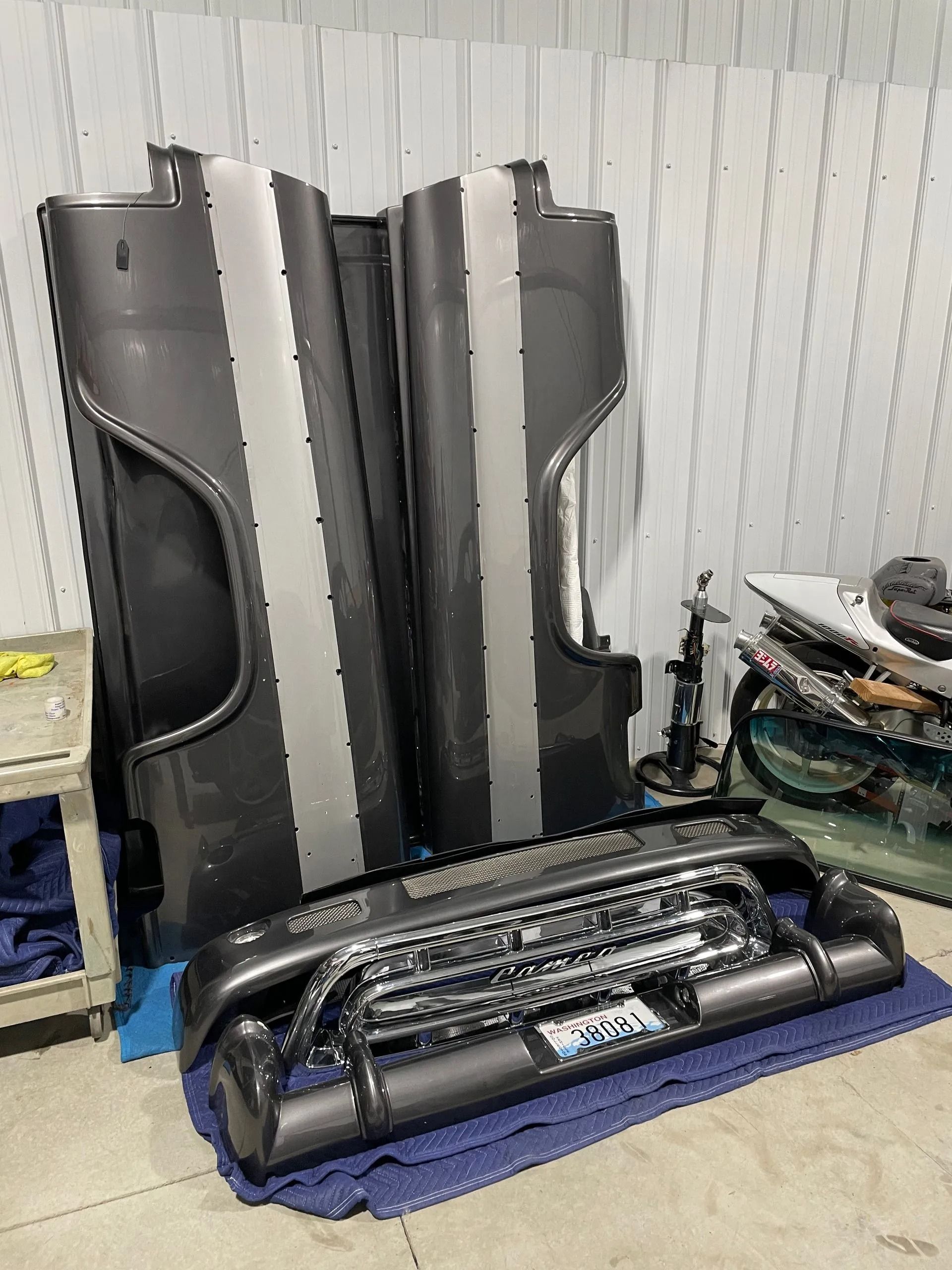 Folded black inflatable boat parts stacked on a blue mat in a workshop.