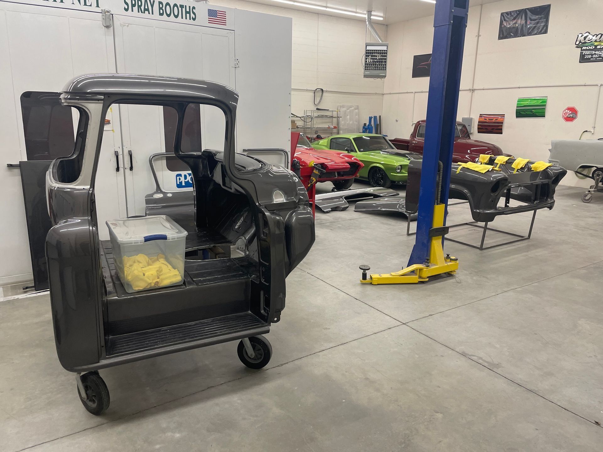 Auto repair shop with a black vehicle, lift, and several go-karts in the background