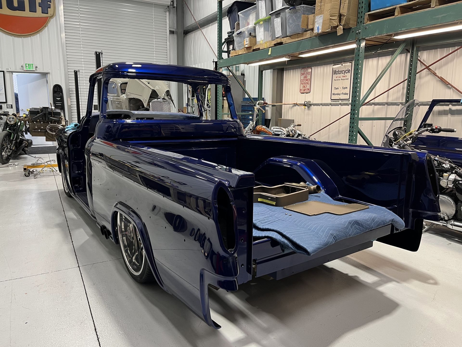 Blue classic pickup truck in a workshop, partly disassembled with front body panels removed