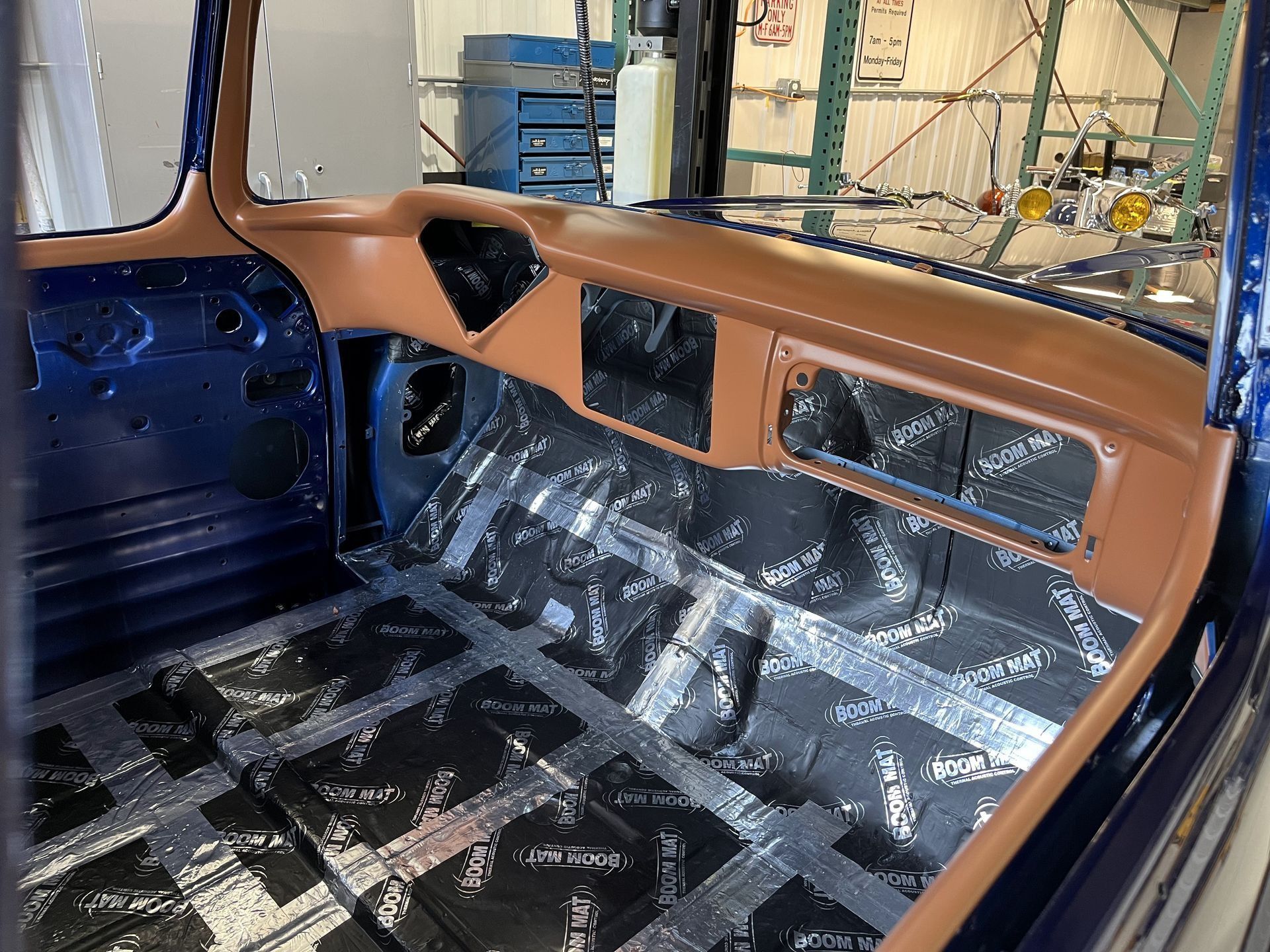 Car interior with tan dashboard and door panels, black floor, and exposed metal in a partially restored vehicle