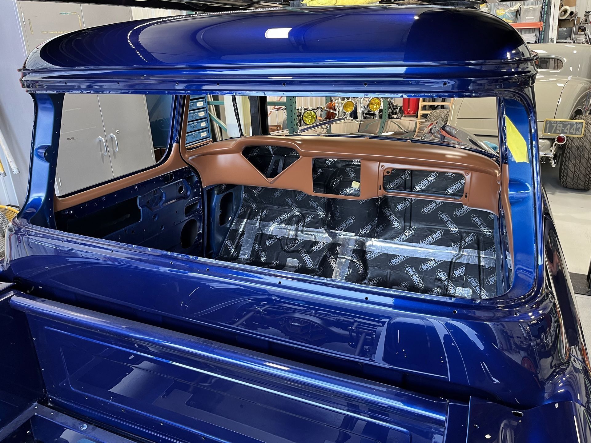 Blue custom car interior with tan seats and glossy roof in a workshop