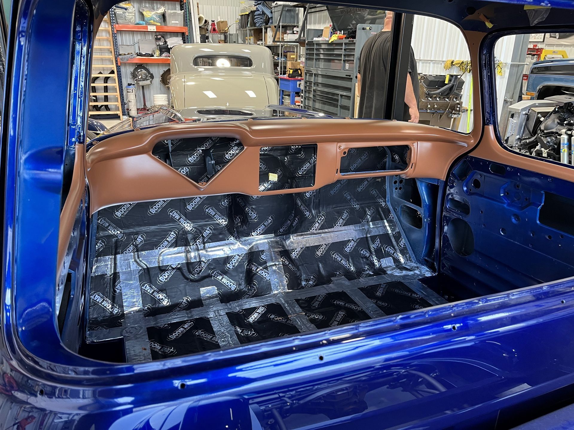 Blue car interior with brown dashboard and plastic-covered cargo area in a workshop