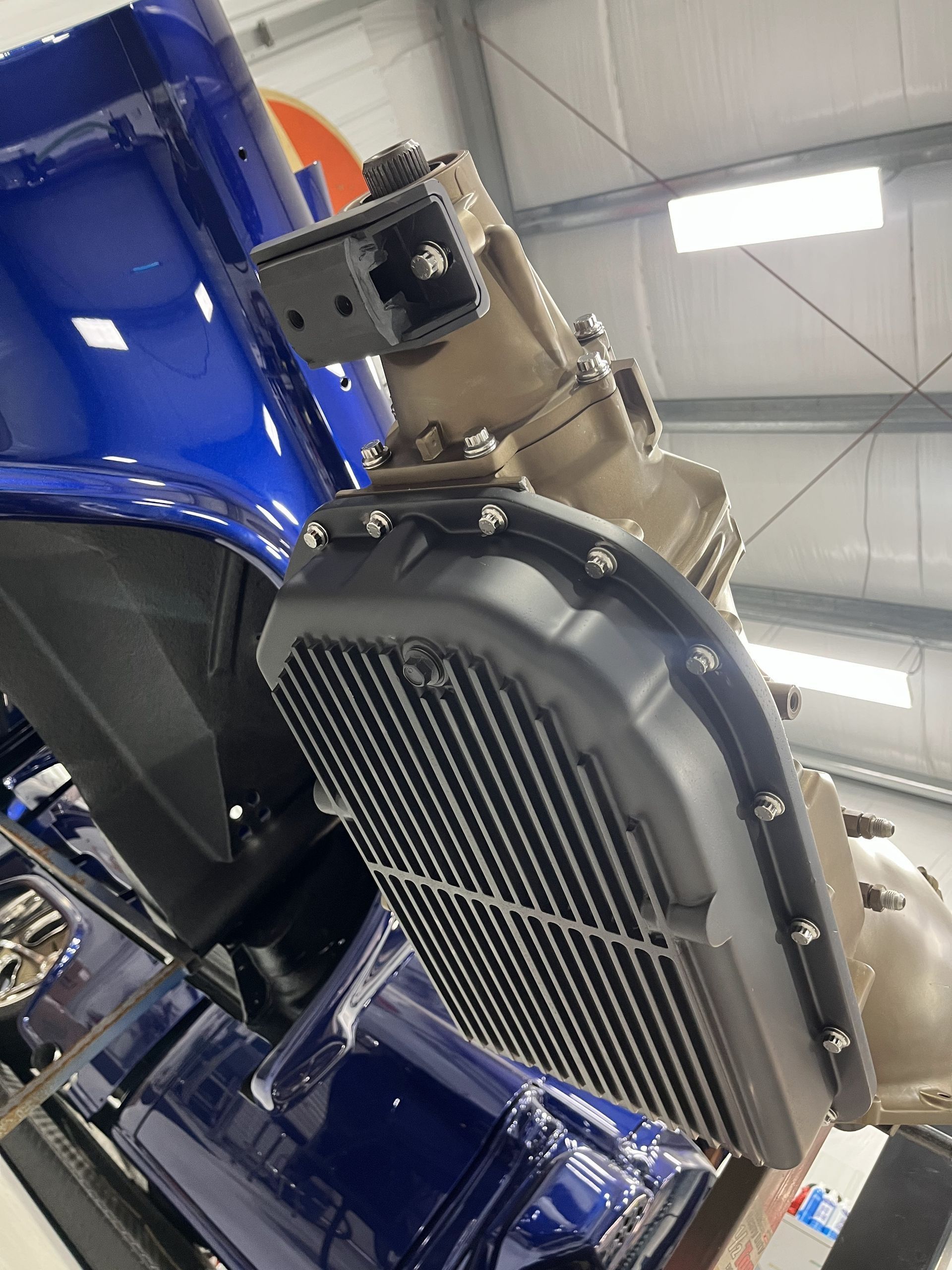 Close-up of a blue race car’s front radiator and engine components in a garage.