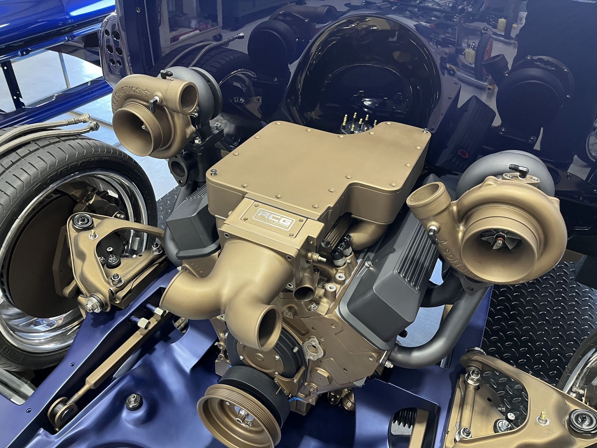 Close-up of a tan and black mechanical engine assembly on a blue frame in a workshop-like setting