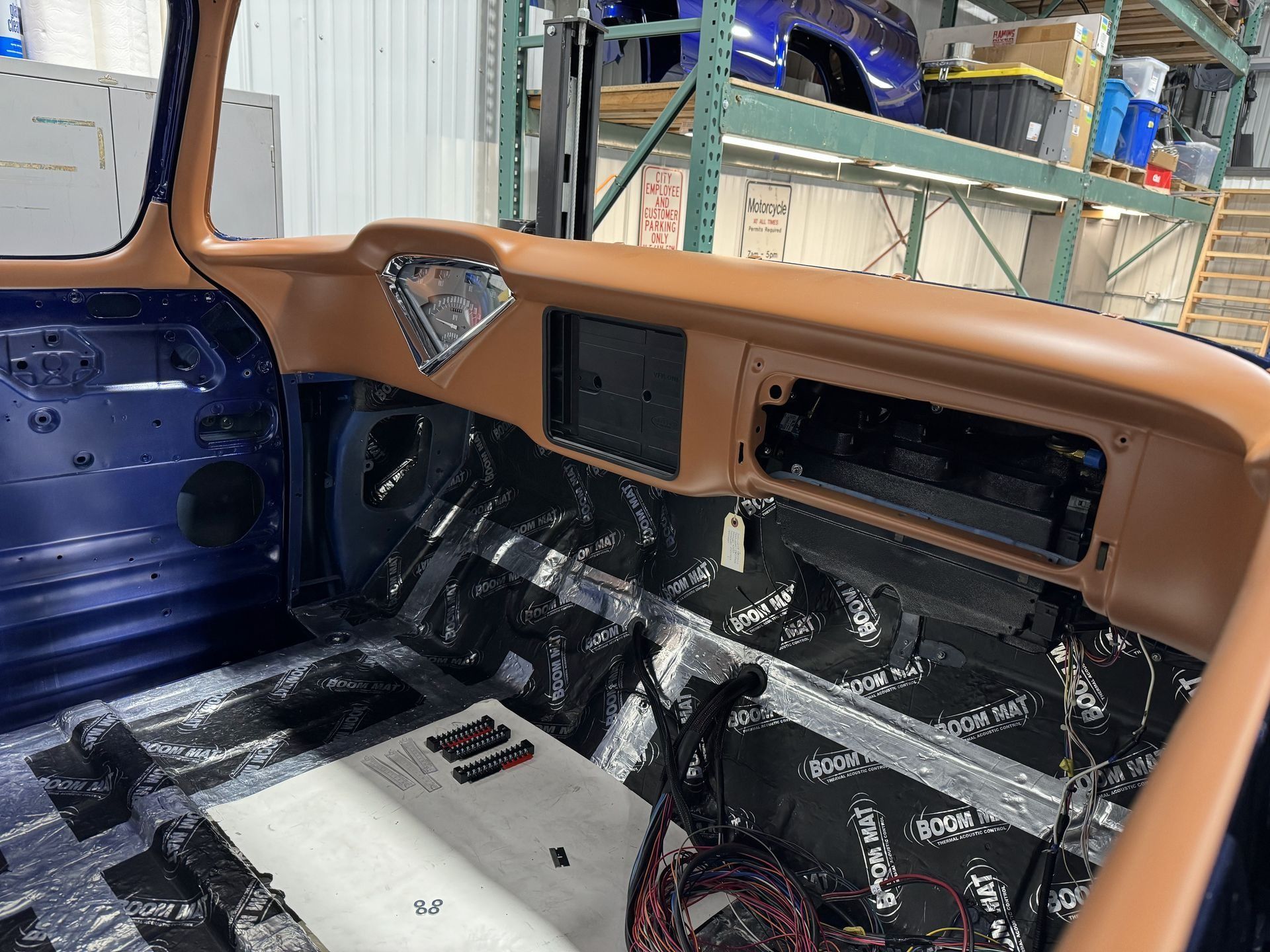 Partially restored car interior with tan dash, blue door panel, and exposed black floor insulation