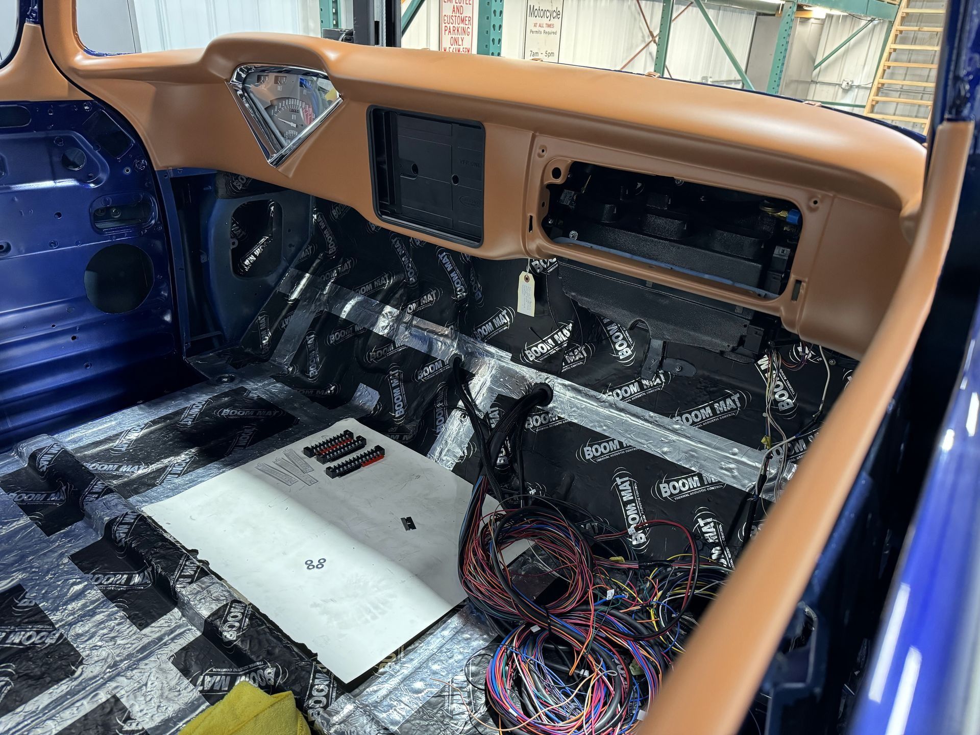 Custom car interior under restoration with tan dashboard, blue door frame, exposed wiring, and stripped floorpan