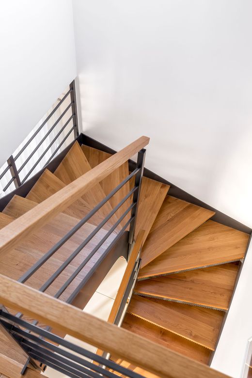 Una scala a chiocciola in legno con ringhiera in metallo in una casa.