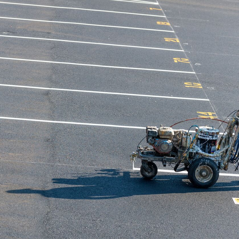 Line striping machine applying fresh parking stall markings on asphalt