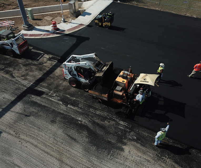 Asphalt paver and roller installing a new parking lot surface in San Antonio