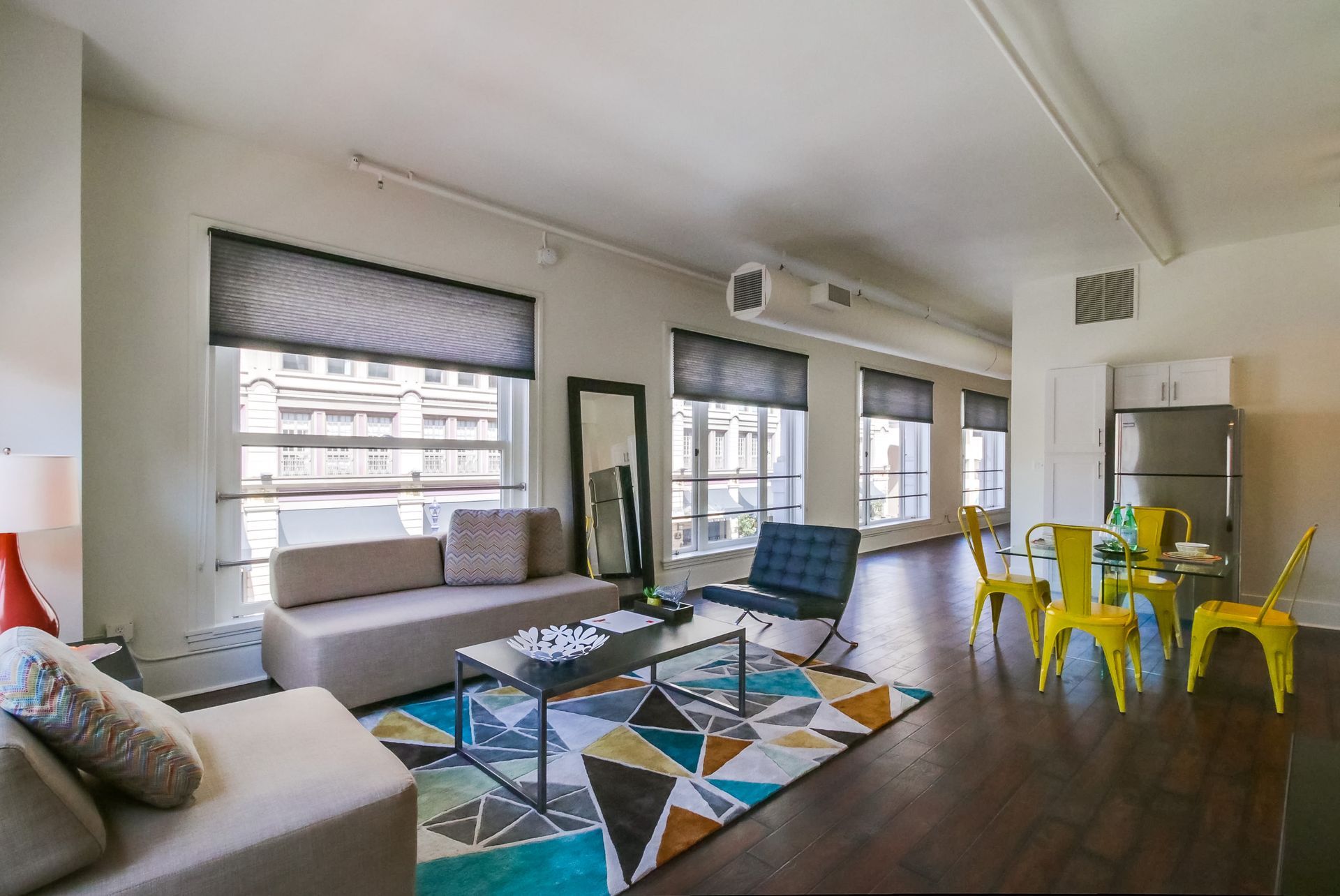 A living room with a couch , chairs , a table and a rug.