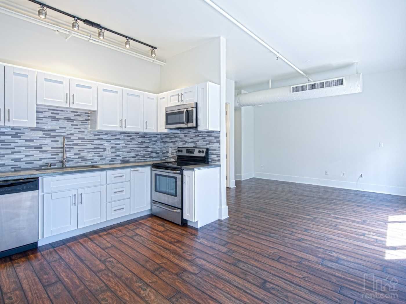 A kitchen with white cabinets , stainless steel appliances , and hardwood floors.