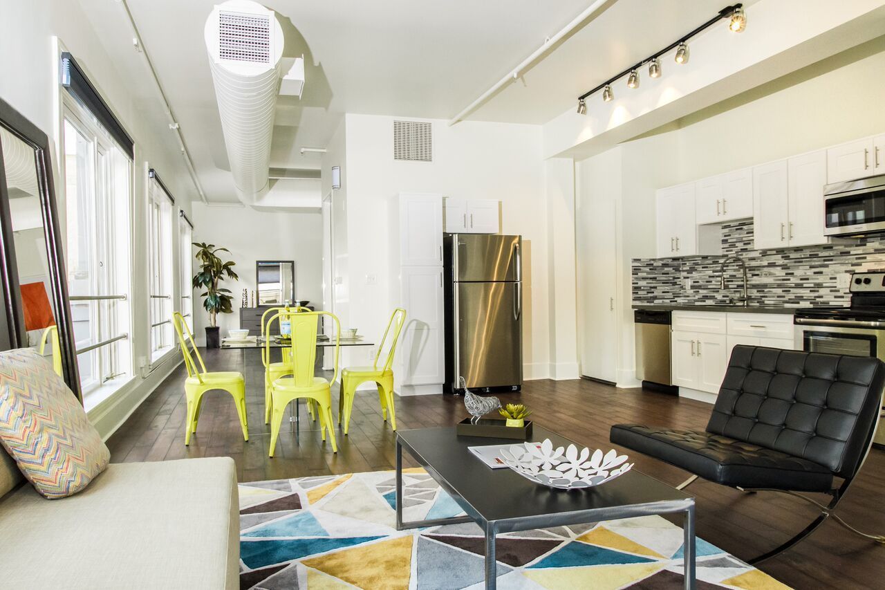 A living room with a couch , table , chairs and a coffee table.