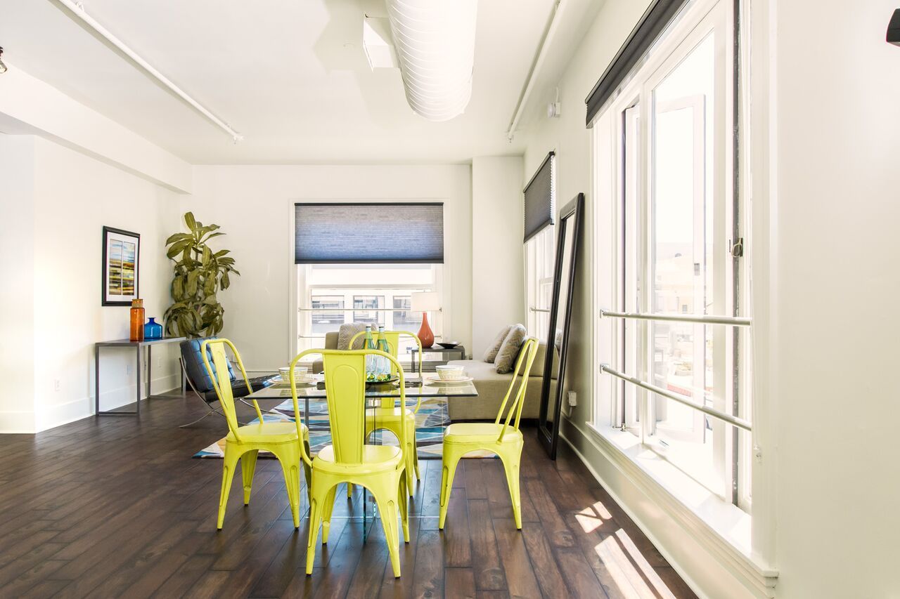 A living room with a dining table and chairs and a large window.