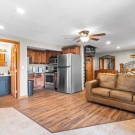 Open living room with kitchen, stainless fridge, tan sofa, and wood flooring