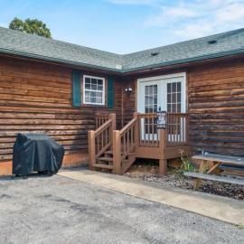 Wooden house patio with steps, white double doors, covered grill, and paved driveway
