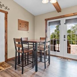Small dining area with tall table and chairs beside glass French doors and a wood-beamed ceiling