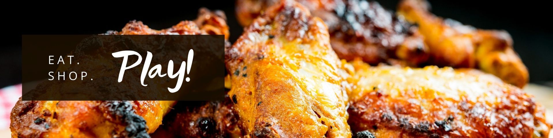 Close-up of crispy fried chicken with a dark label reading “Eat. Shop. Play!”