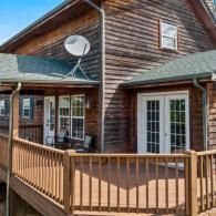 Wooden cabin deck with railing, French doors, and a satellite dish on the roof