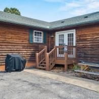 Wooden house exterior with small porch steps, grill, and paved driveway in front