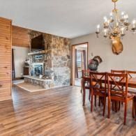 Cozy dining room with wooden table, chandelier, stone fireplace, and hardwood floors
