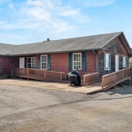 Brick building with ramp access and a grill on a paved lot under a clear sky