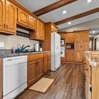 Bright kitchen with wooden cabinets, white appliances, and wood-look flooring