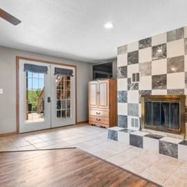 Bright living room with tiled fireplace, wood floor, French doors, and a wooden cabinet