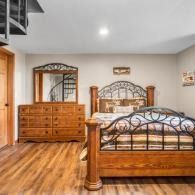 Bedroom with matching wooden bed and dresser, warm wood flooring, and neutral walls