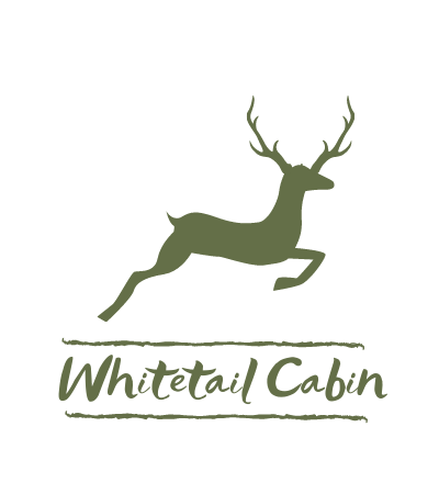 Green leaping deer logo above “Whitetail Cabin” text on white background