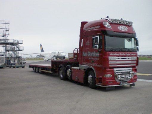 Red Ian Gordon with transport trailer  at an airport with plane in the background