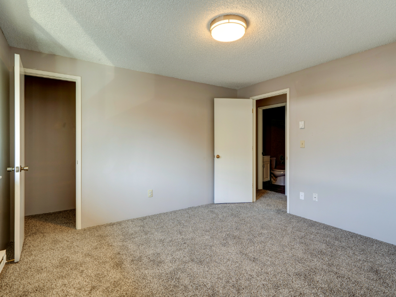 An empty bedroom with a closet and a toilet.