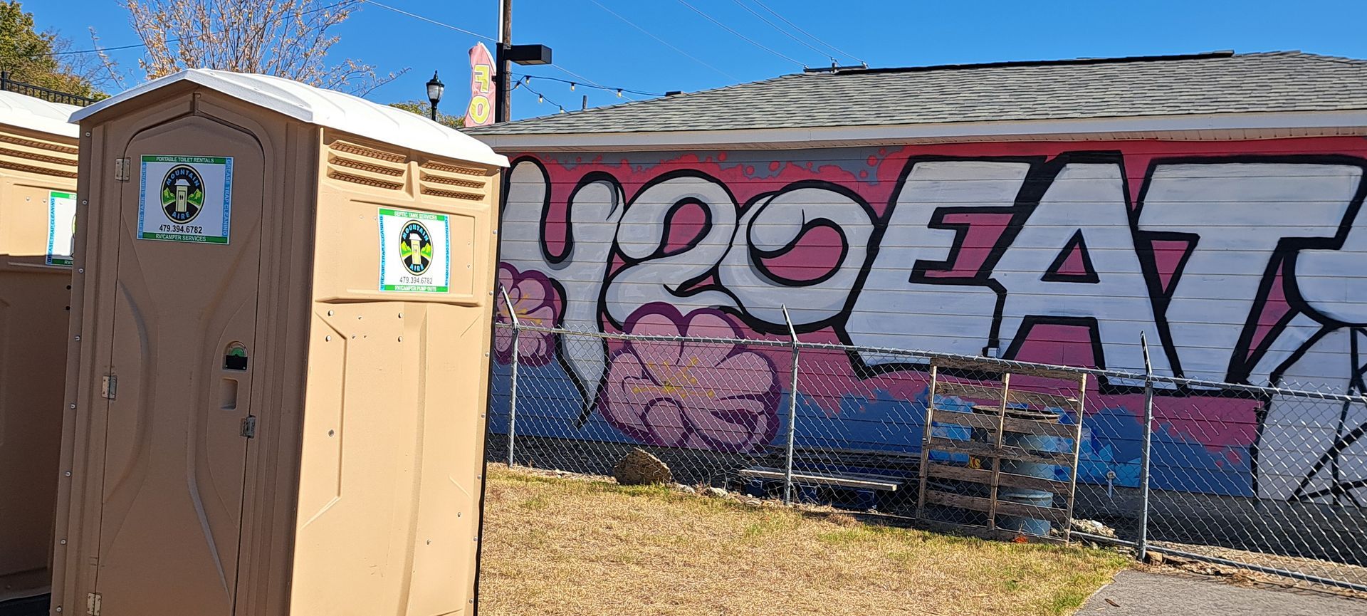 A group of portable toilets are sitting in front of a graffiti covered wall.