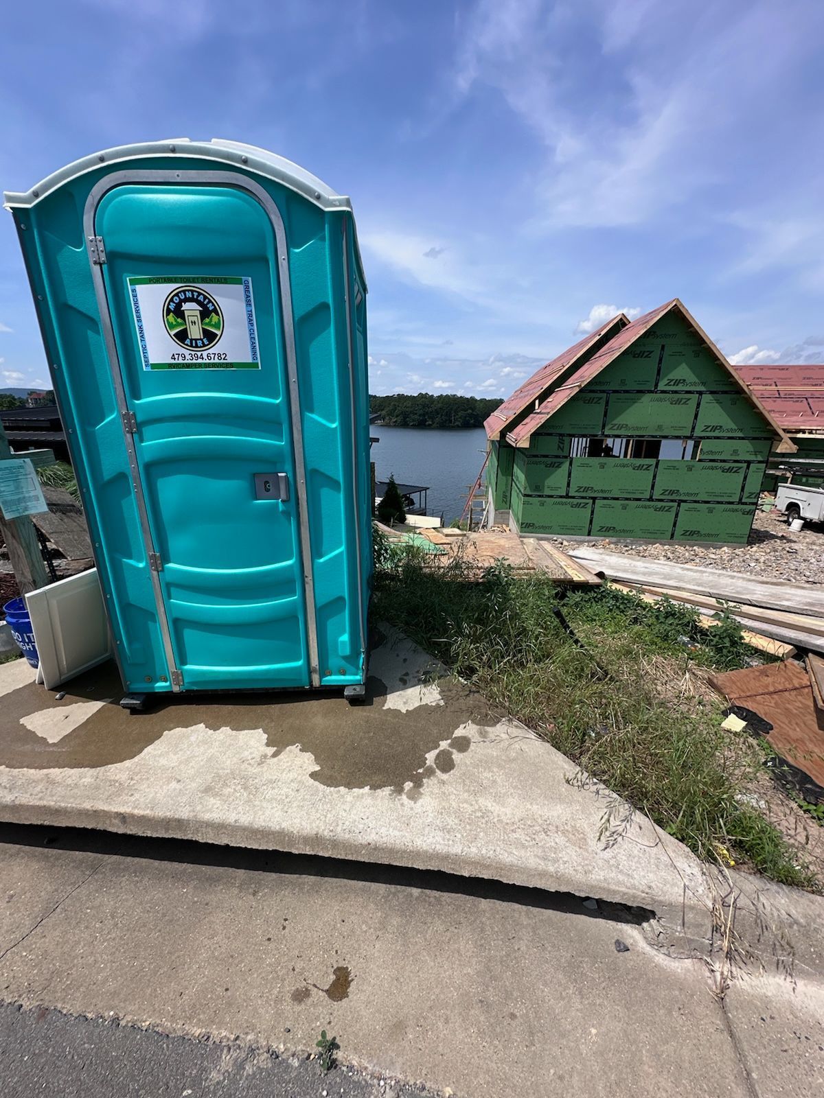 A portable toilet is sitting on the side of the road next to a building under construction.