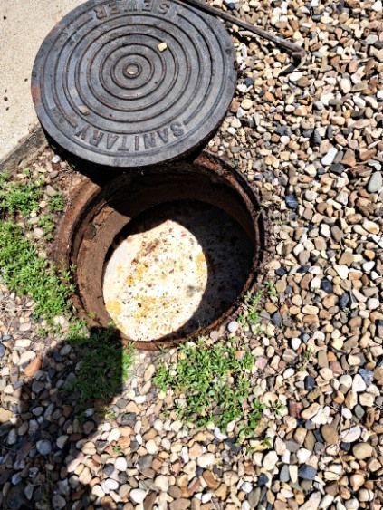 A manhole cover is sitting on top of a pile of gravel.