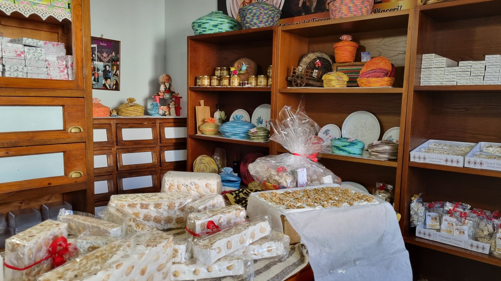 Interno del negozio con scaffali pieni di dolcetti, regali e decorazioni, tra cui torrone confezionato.
