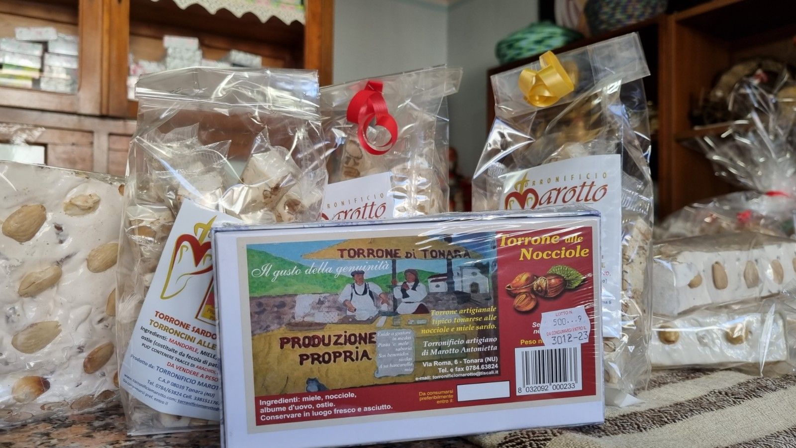 Esposizione di dolci al torrone incartati in un negozio, tra cui una scatola con l'etichetta