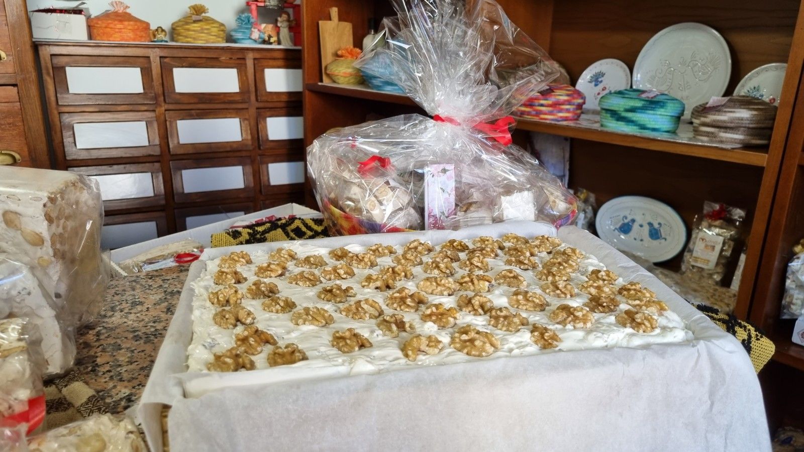 Torta con noci su un tavolo in un negozio, cesti regalo e scaffali sullo sfondo.