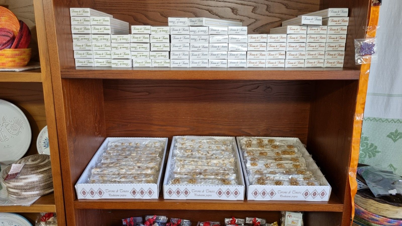 Scaffale in legno con scatole di dolcetti, disposte in file. Alcune scatole sono sul ripiano superiore, altre su vassoi sottostanti.