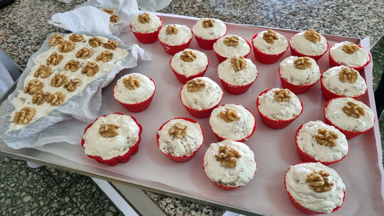 Vassoio di cupcakes e quadrotti di torta con glassa bianca e noci.