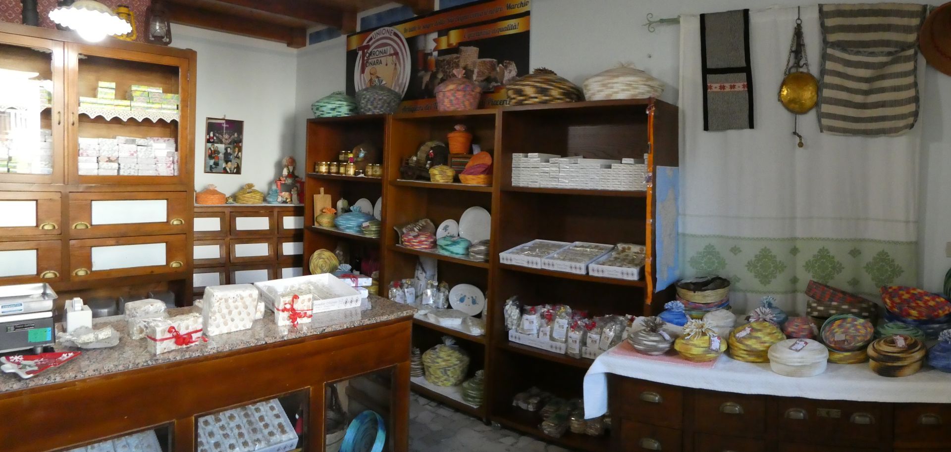 Interno di un negozio che espone vari articoli per la casa su scaffali e un bancone.