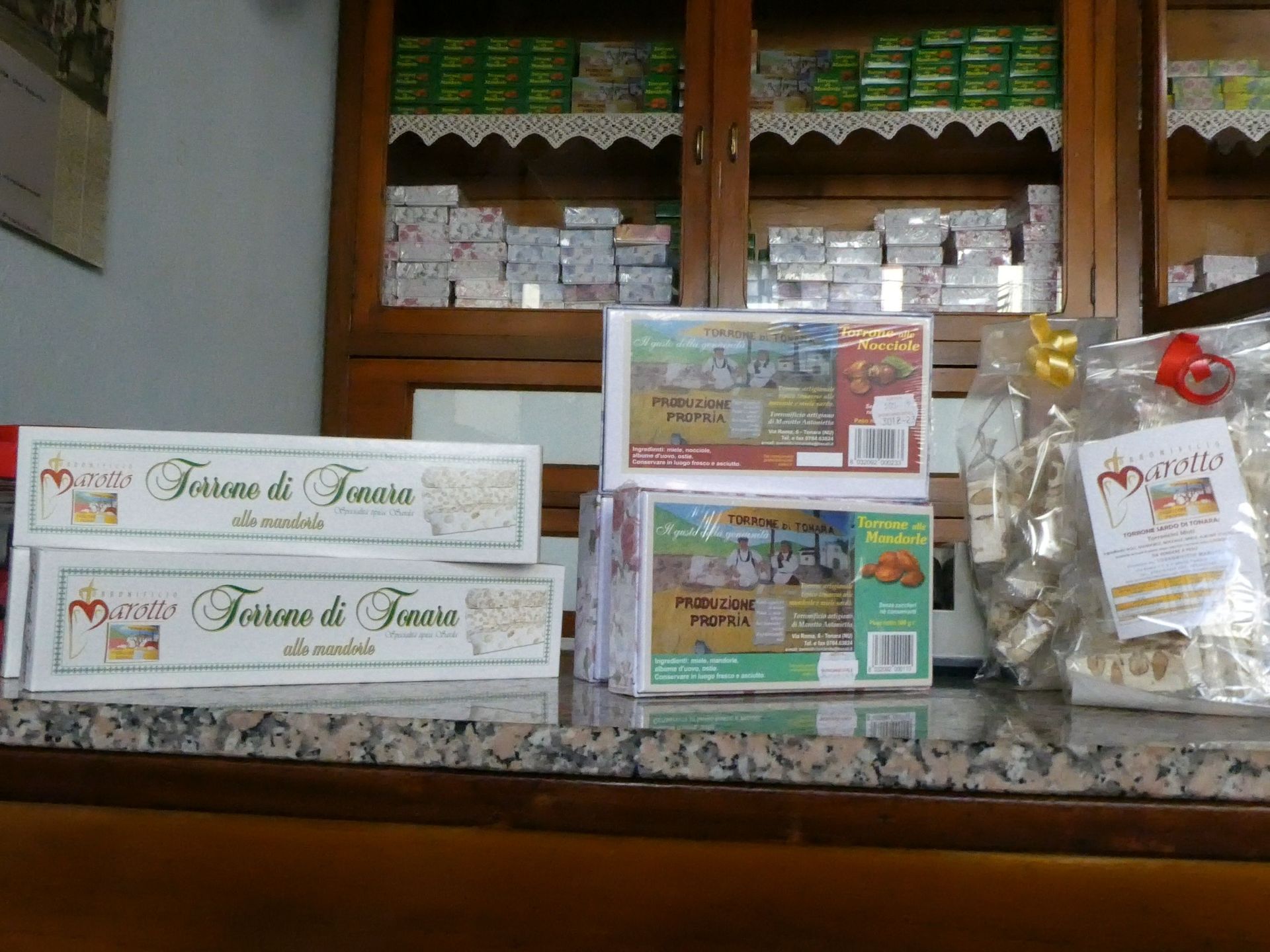 Un bancone di un negozio che espone dolciumi confezionati e insegne, con scaffali di legno che ospitano altri prodotti sullo sfondo.