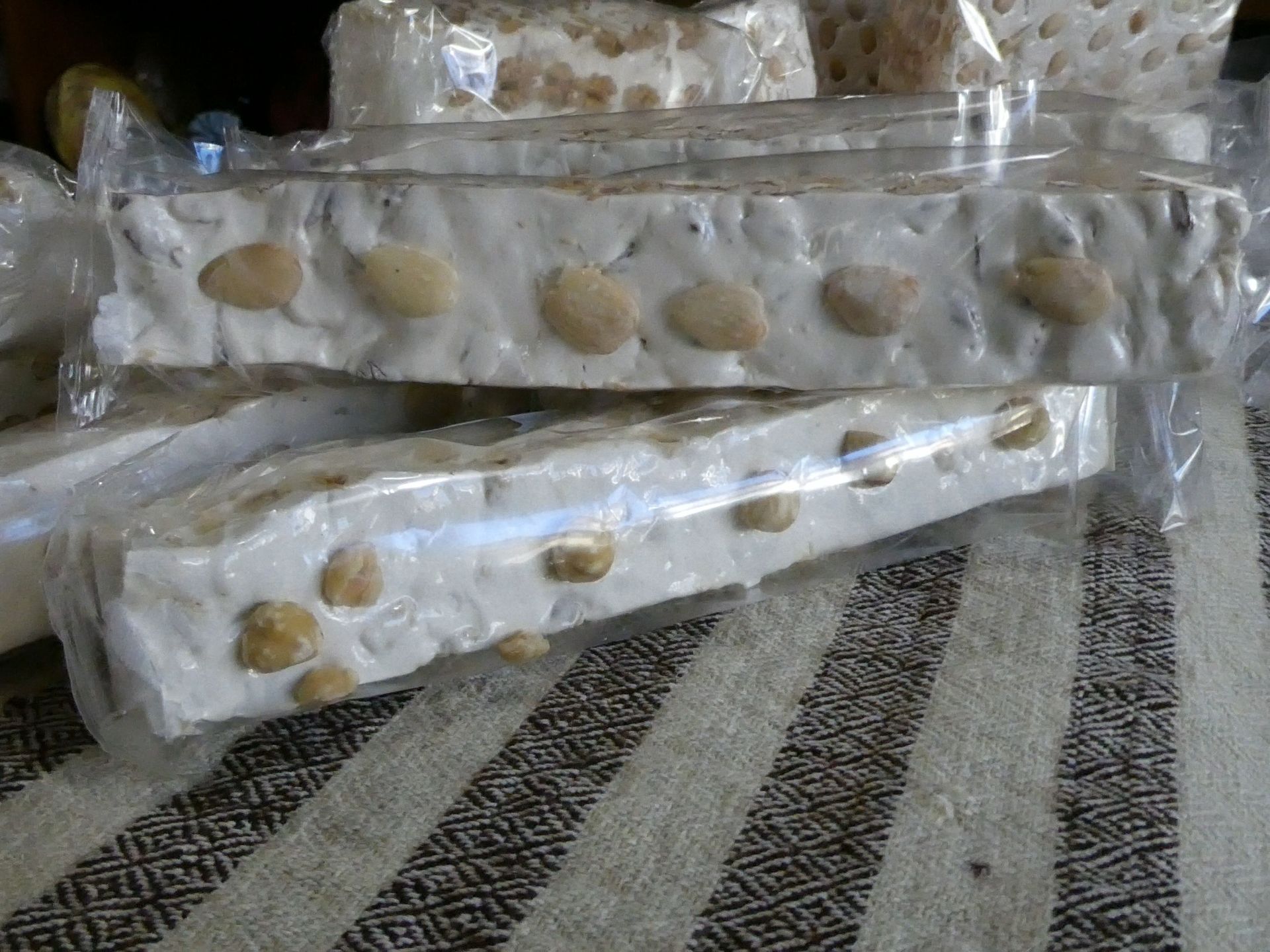 Barrette di torrone in confezioni di plastica trasparente, con noci visibili all'interno.