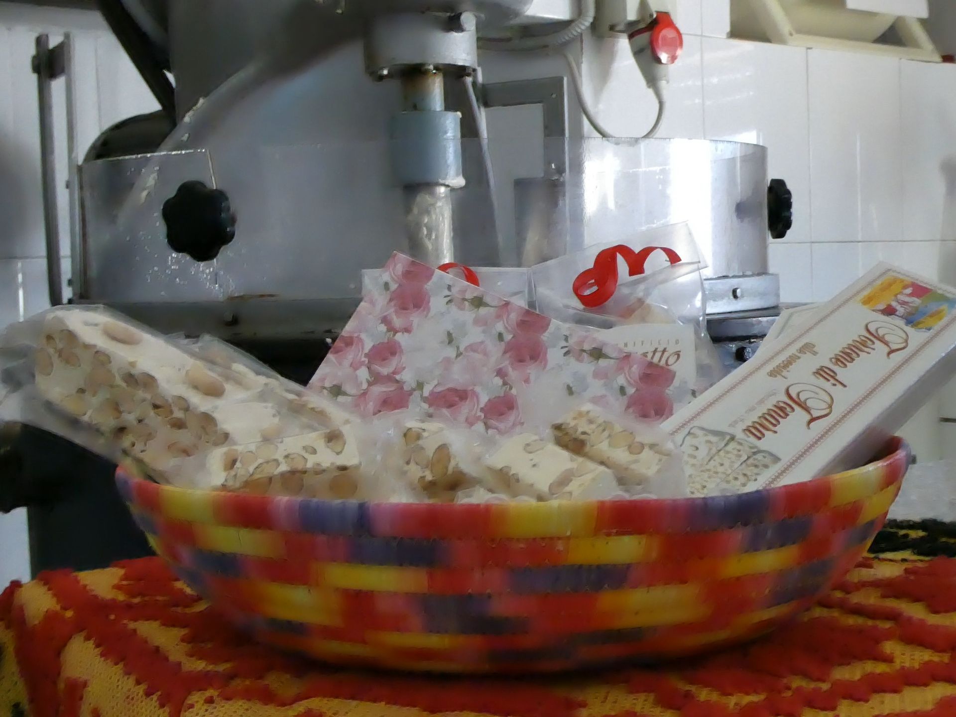 Cestino di torrone con una macchina affettatrice sullo sfondo.