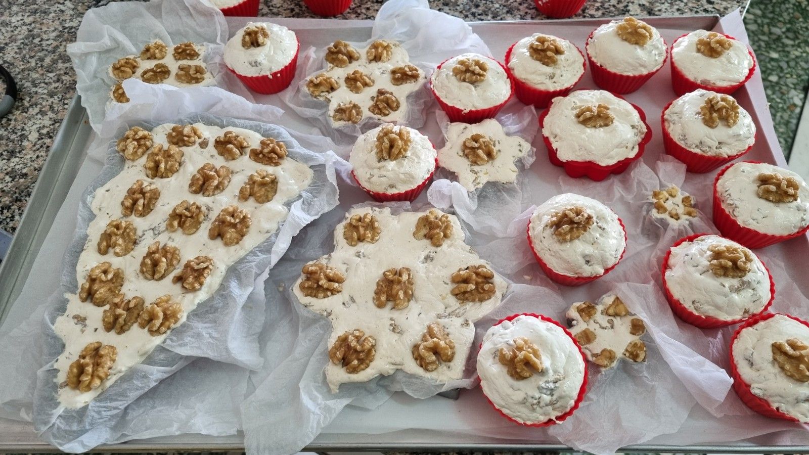 Vassoio di pasticcini assortiti con glassa bianca e guarnizioni di noci.