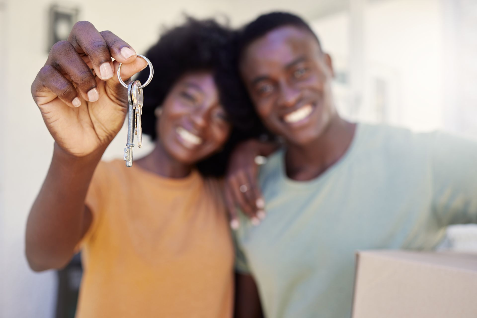Couple holding up keys, smiling, possibly at a new home.